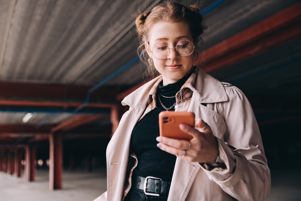 Young woman with glasses looking at a phone