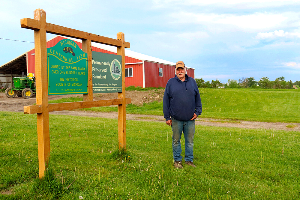 Lifelong farmer Tom Holstege stands next to his Farmland Preservation sign on his property in Zeeland Township. 